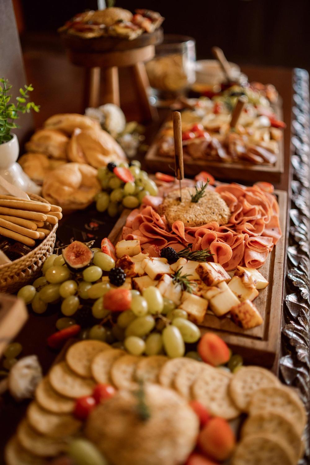 Grazing table styled with cheeses, grapes, breads and charcuterie at an event